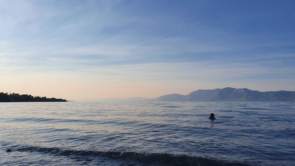 ήρεμη θάλασσα στο σούρουπο, στο φόντο βουνά