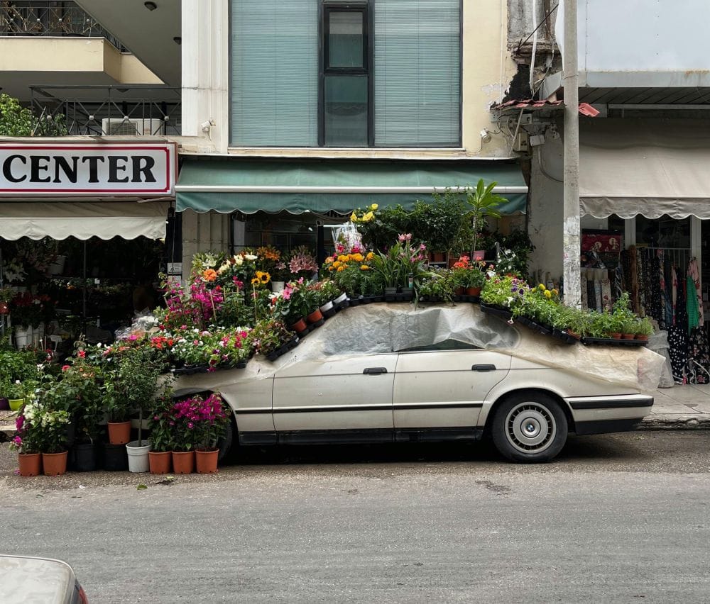 παρκαρισμένο αυτοκίνητο από το πλάι, όλο το επάνω μέρος του είναι καλυμμένο με γλάστρες με φυτά 